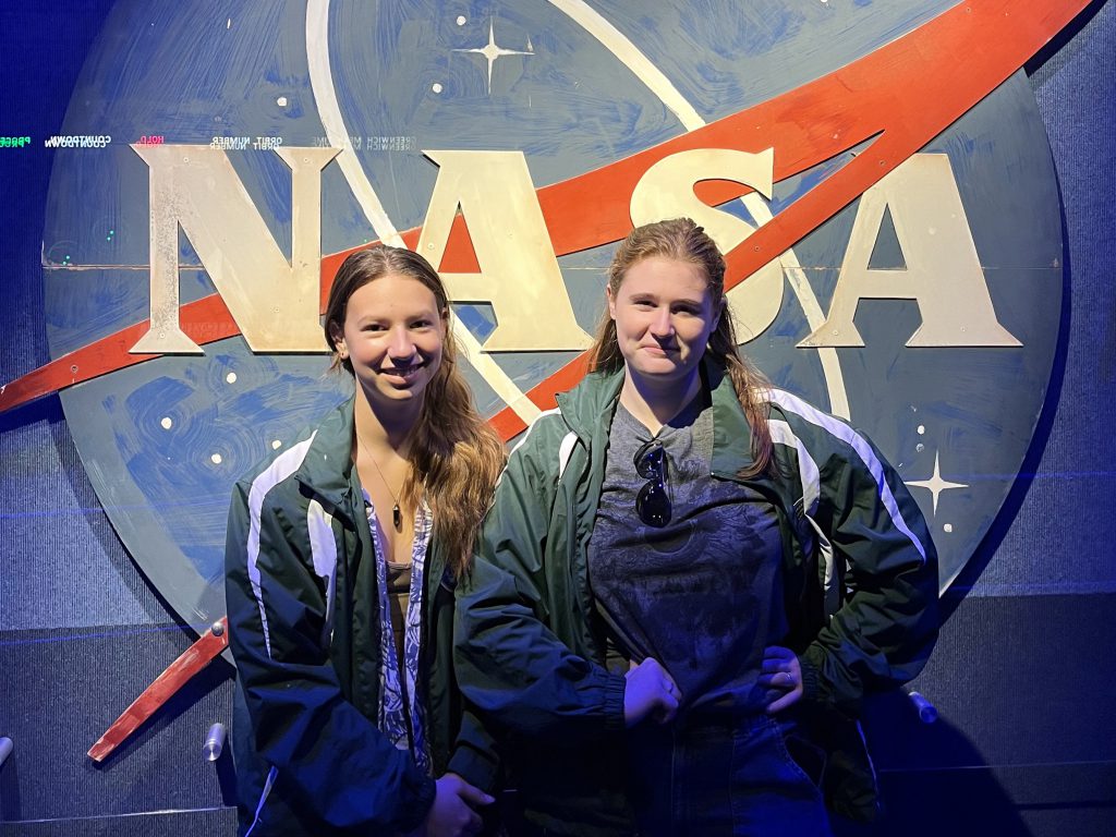 Image of two teen girls standing in front of NASA sign