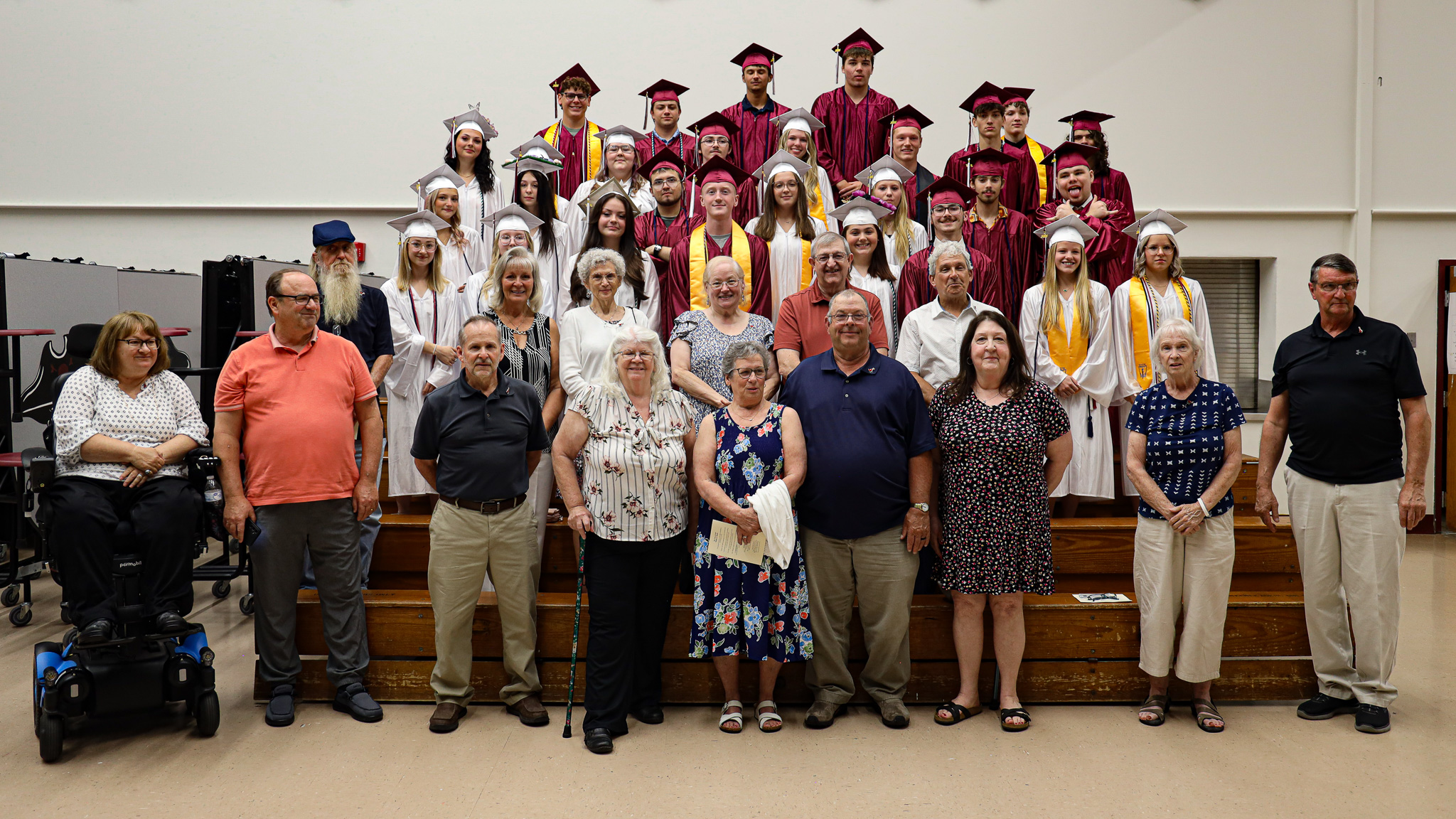 Group of adults posing next to group of students wearing caps and gowns