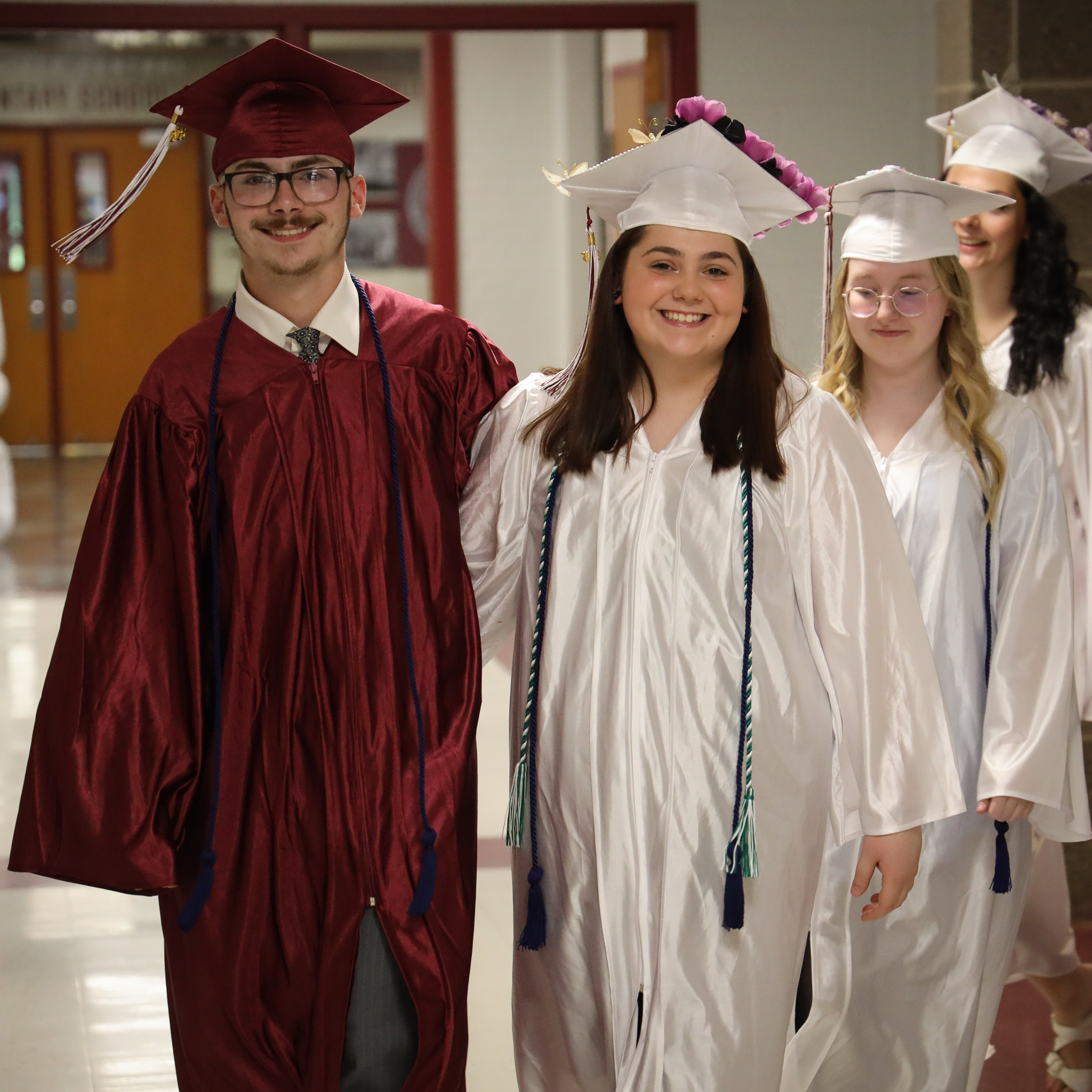 Two students standing side by side wearing cap and gowns