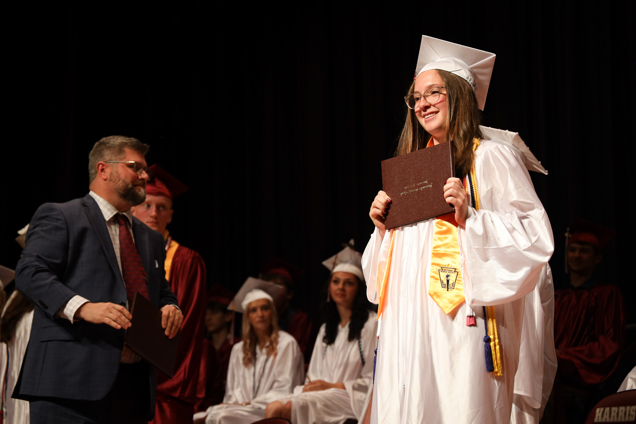 Student holding diploma while wearing cap and gown