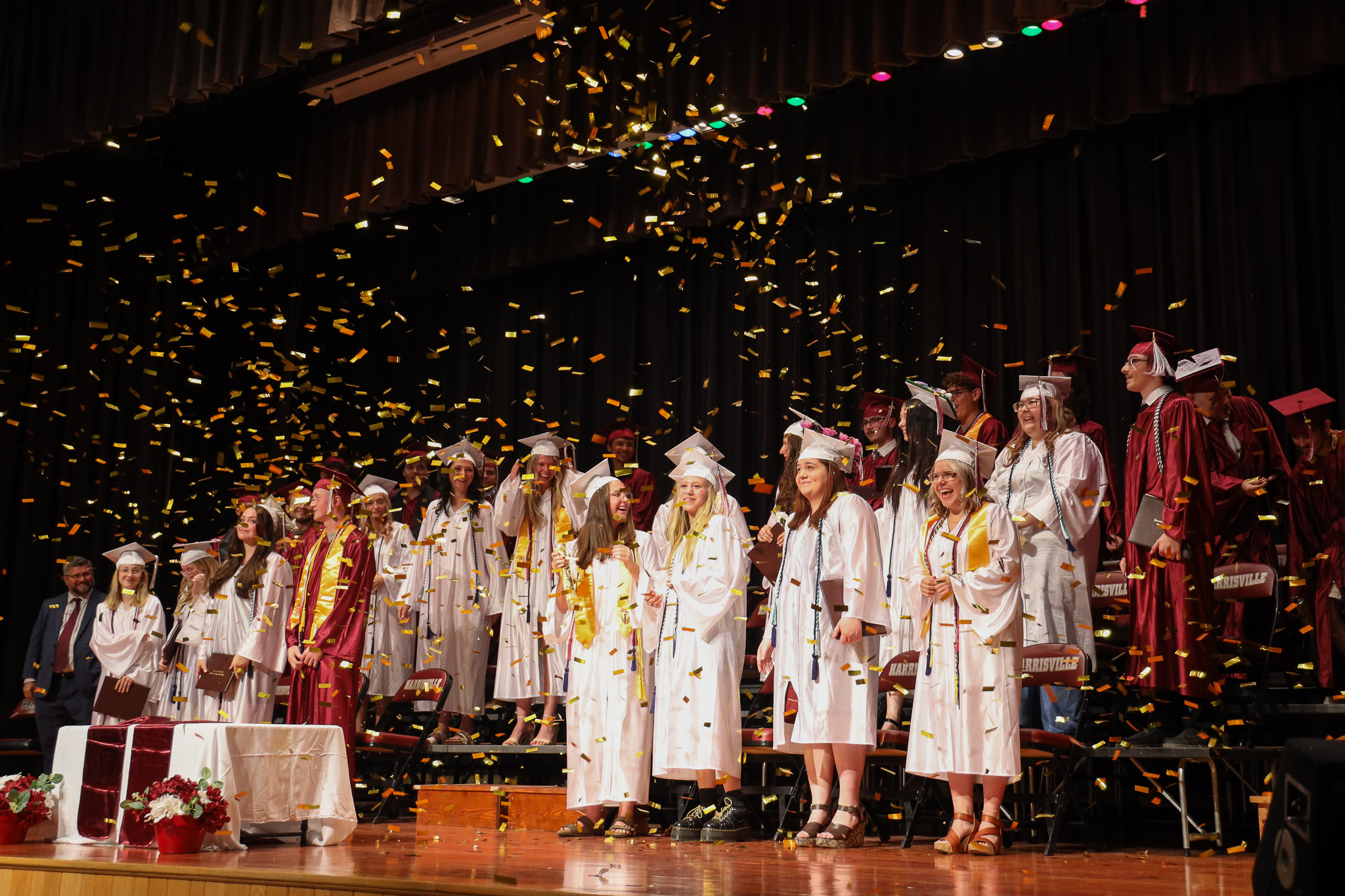 Confetti flies in front of several students wearing commencement caps and gowns