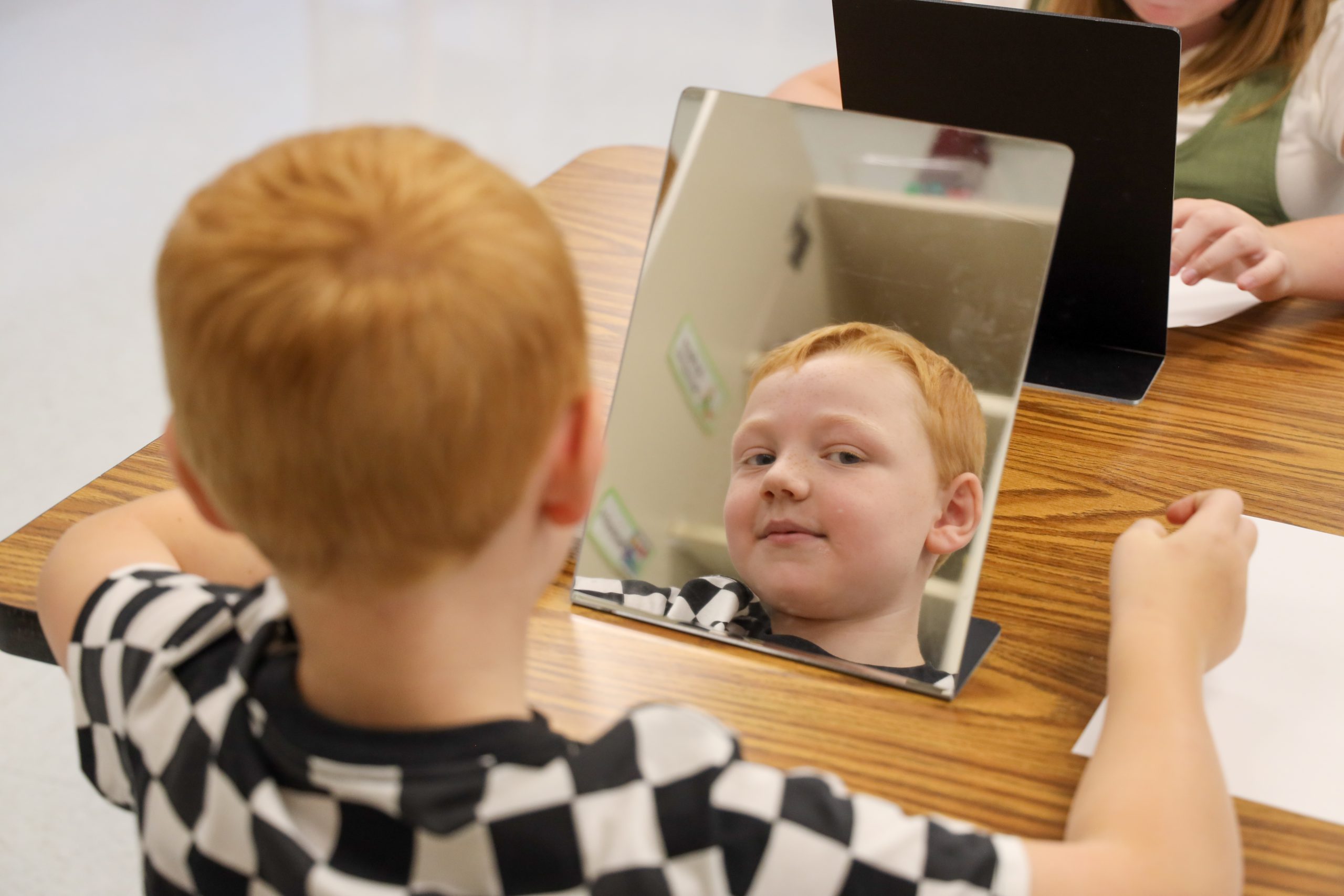 A boy looks into the mirror on a table