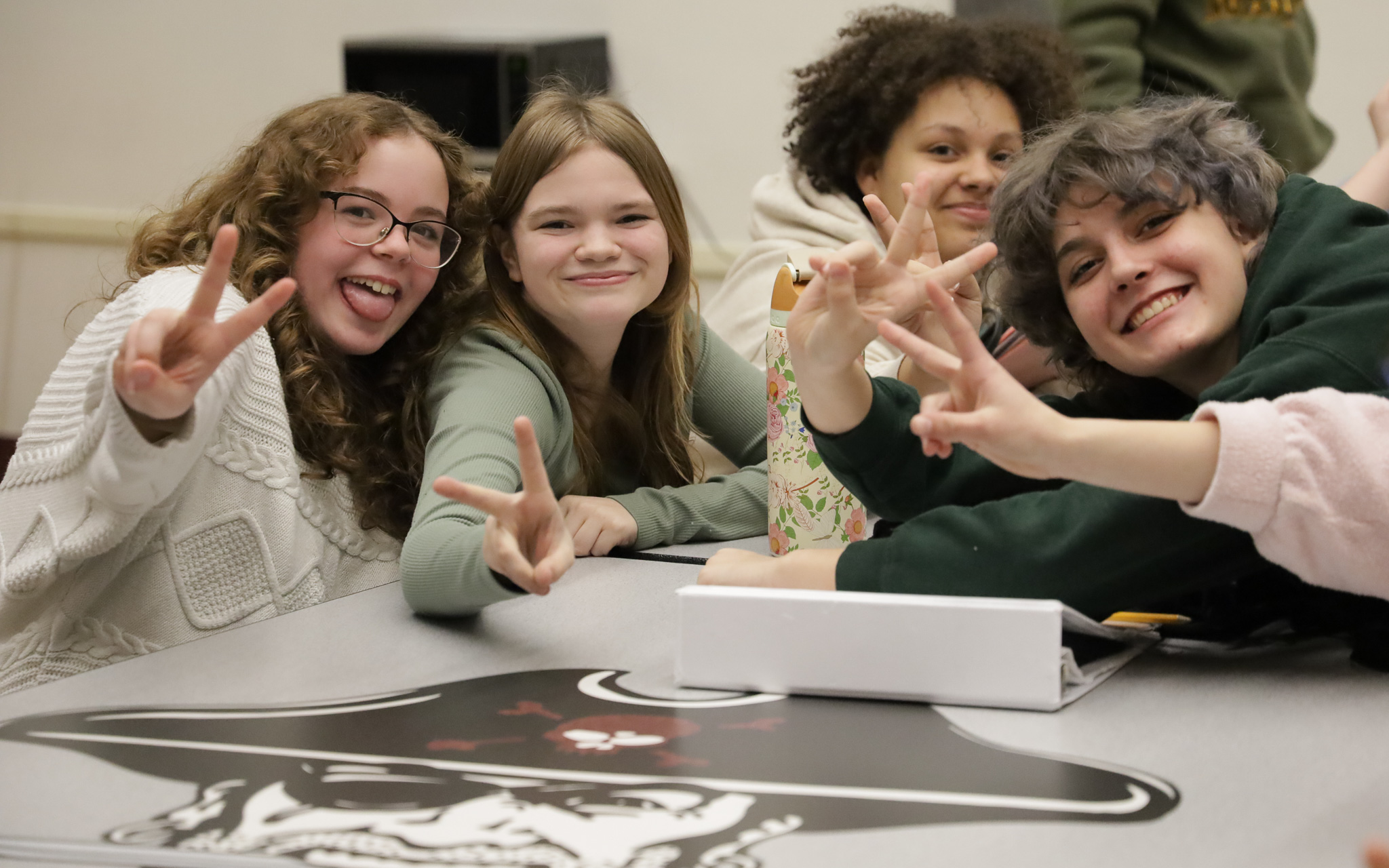 Four students smile and make peace signs at the camera.