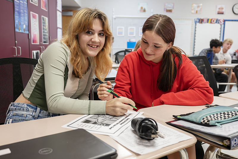 Two students work in a classroom.